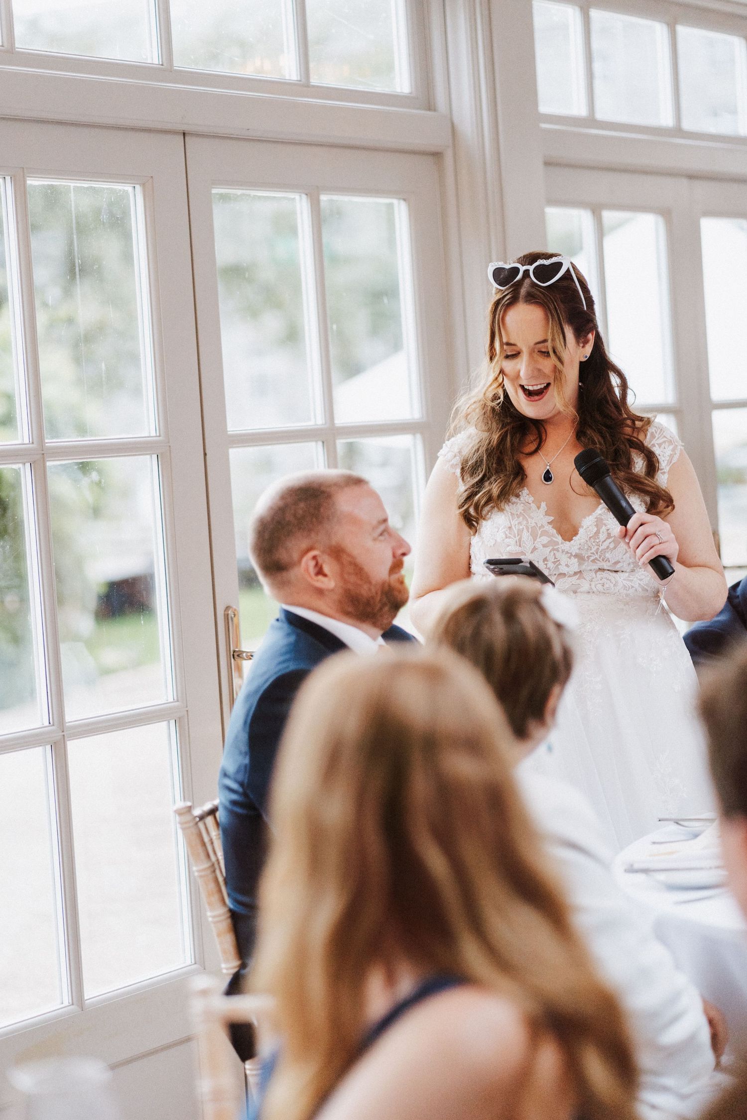 Joyful laughter fills a bright sunlit room during a wedding celebration.