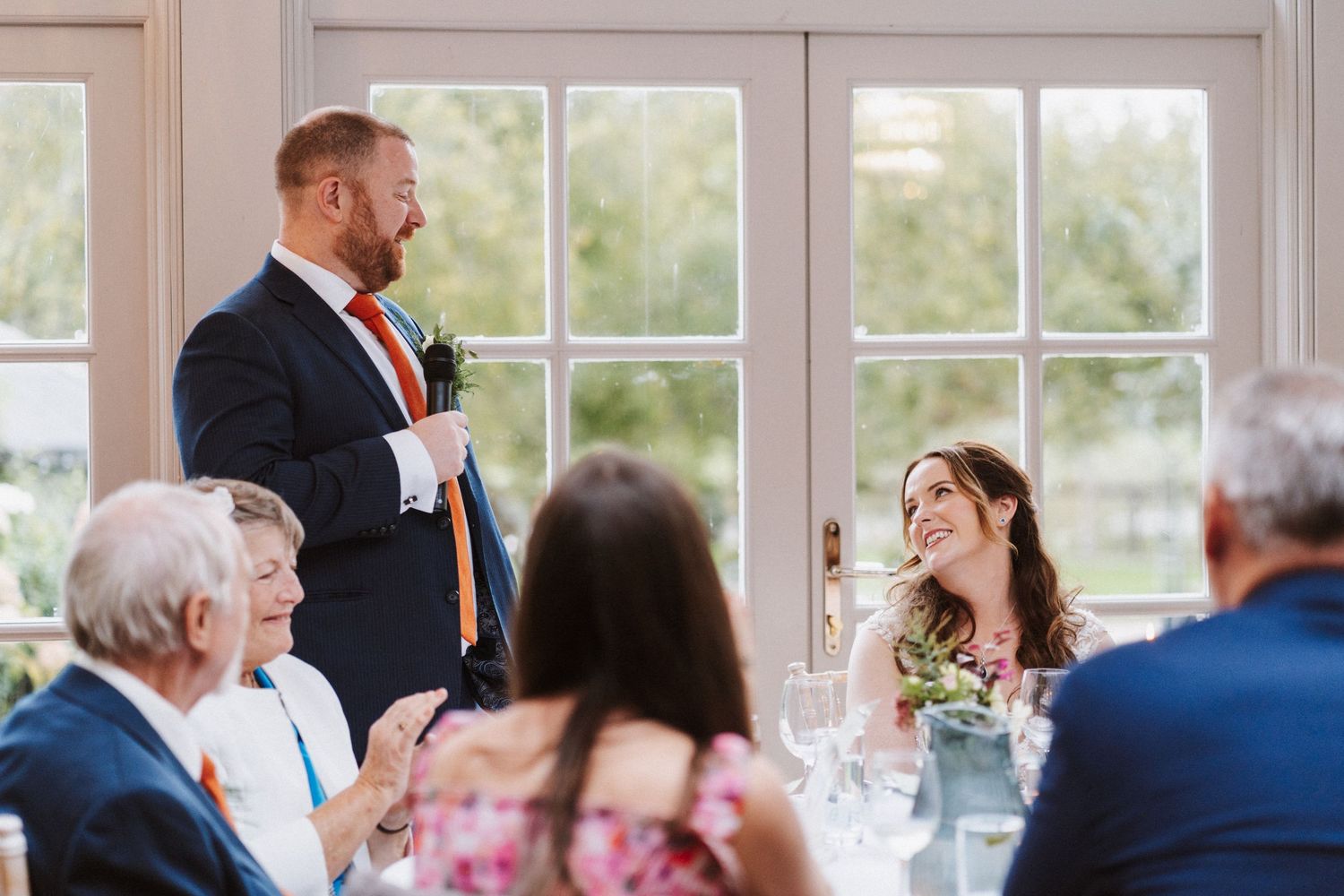 Wedding reception venue with large windows and natural light streaming into dining area.