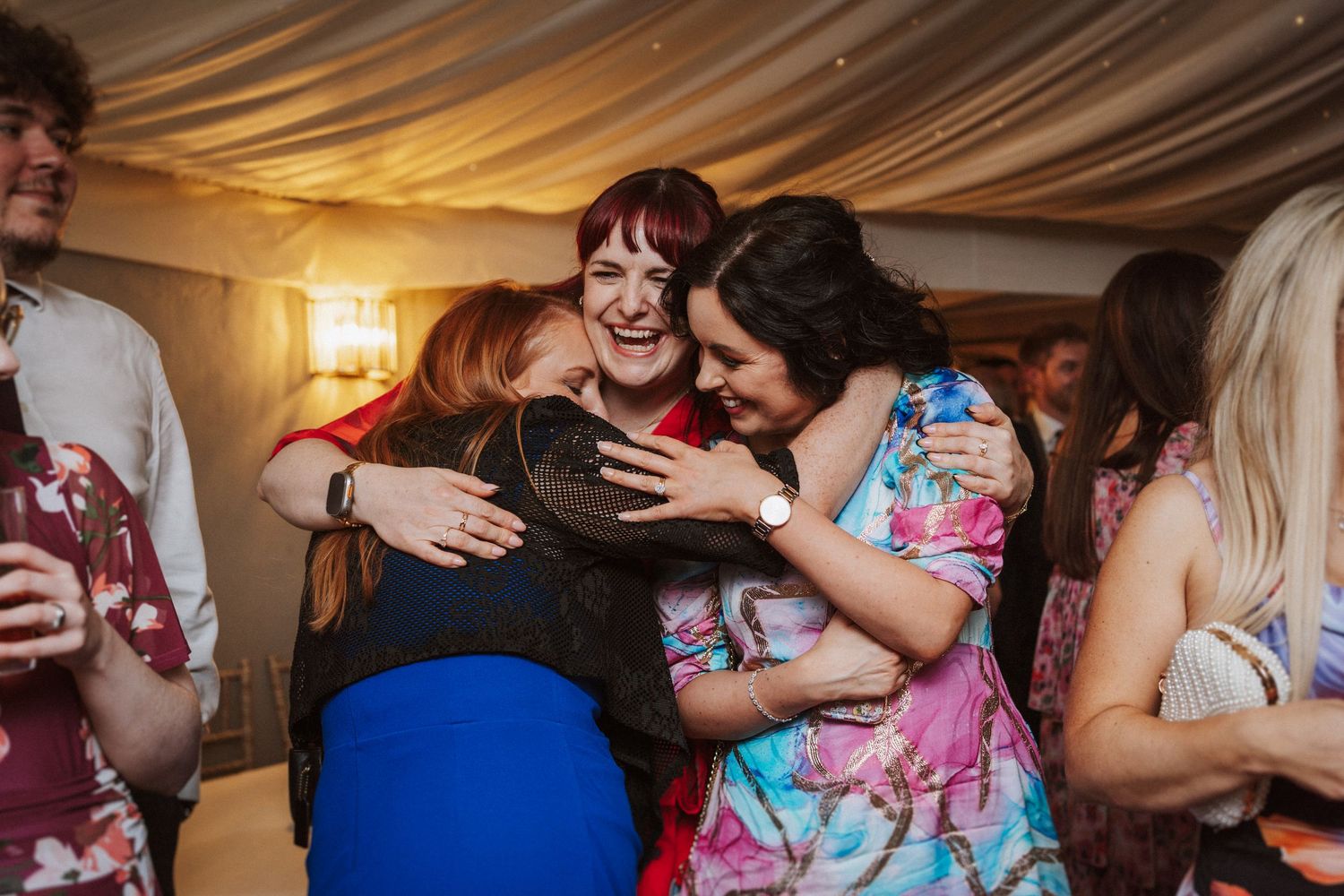 Wedding reception guests dancing and celebrating under draped fabric ceiling decorations.