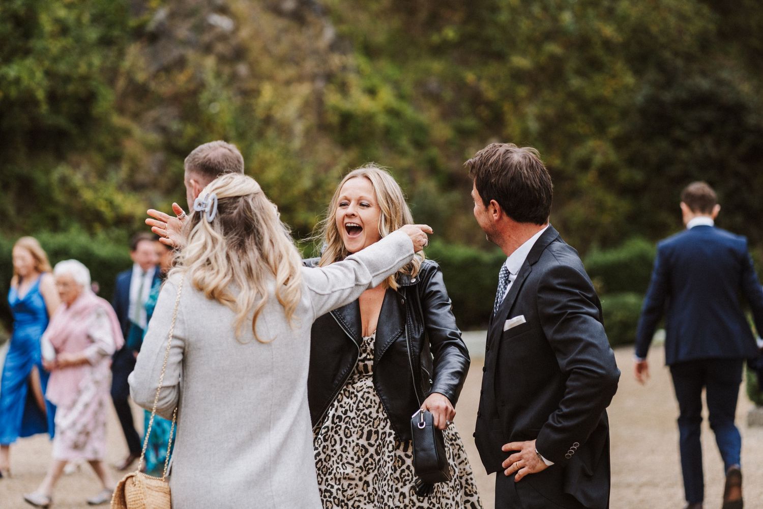 Wedding party members walk together on a garden path during an autumn celebration.