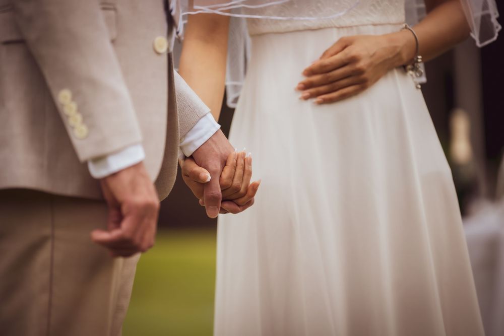 Close-up view of hands holding during an outdoor wedding ceremony with soft natural lighting.