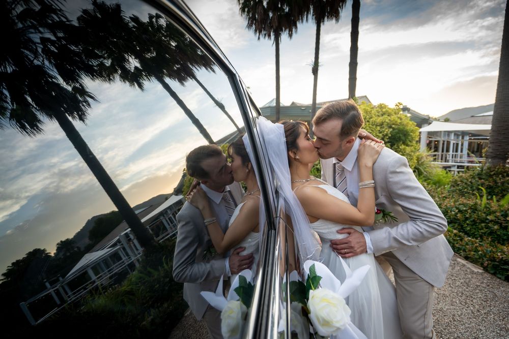 A couple shares a romantic dance on a porch at sunset with palm trees in the background.