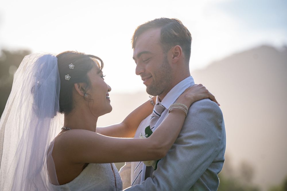 Romantic silhouettes of a bride and groom dancing together at sunset with a dreamy backlit glow.