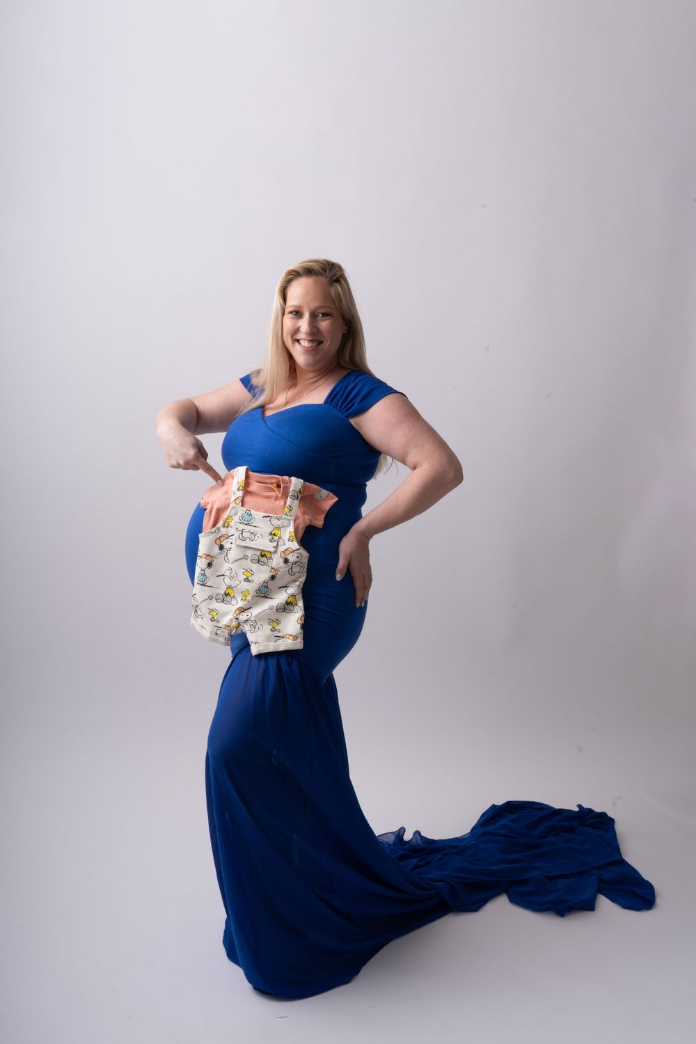 Artistic maternity photos of woman in flowing navy dress posing with vintage book.