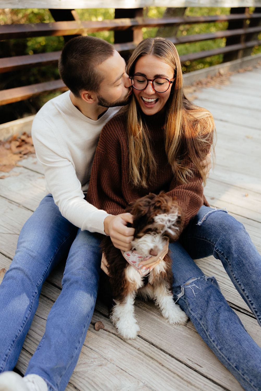 A couple sharing a joyful moment with their small dog on a wooden deck.