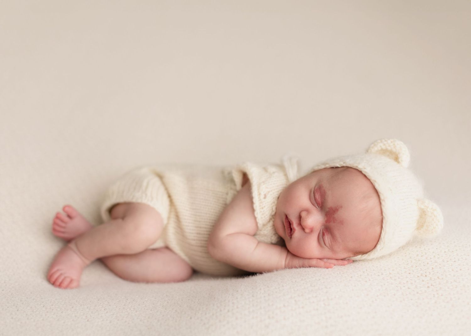 A sleeping newborn baby lying on a soft cream colored blanket in a series of connected photos.