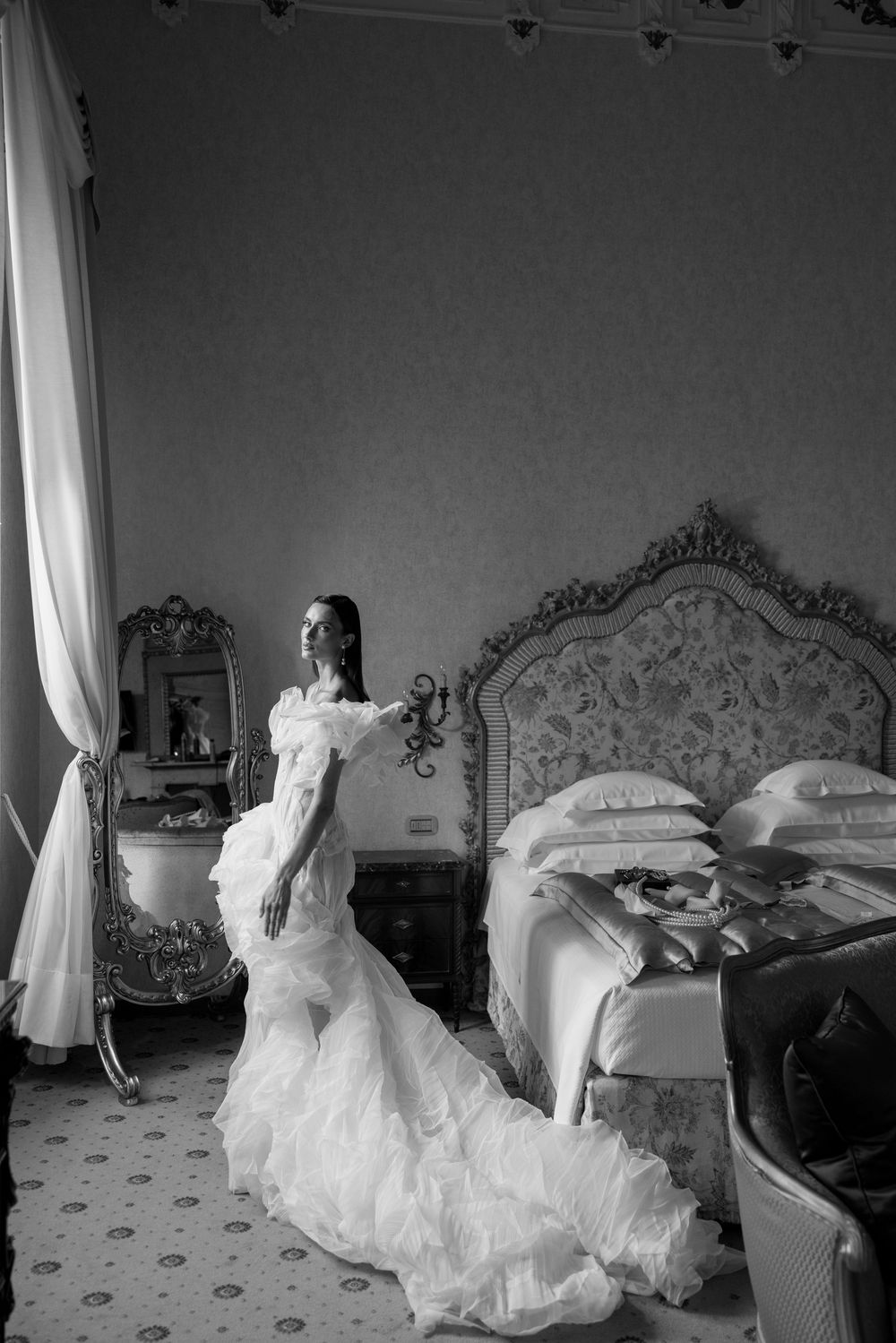 A dramatic black and white photograph of a flowing white dress against an ornate bedroom setting.
