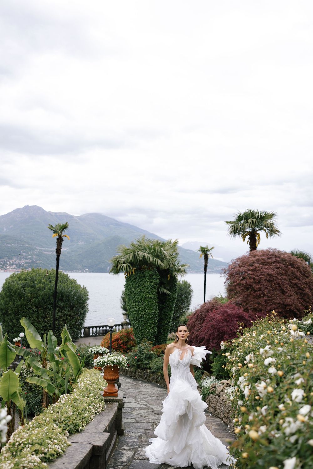 A scenic wedding venue overlooking Lake Como in Italy with lush gardens and stone pathways along the water.