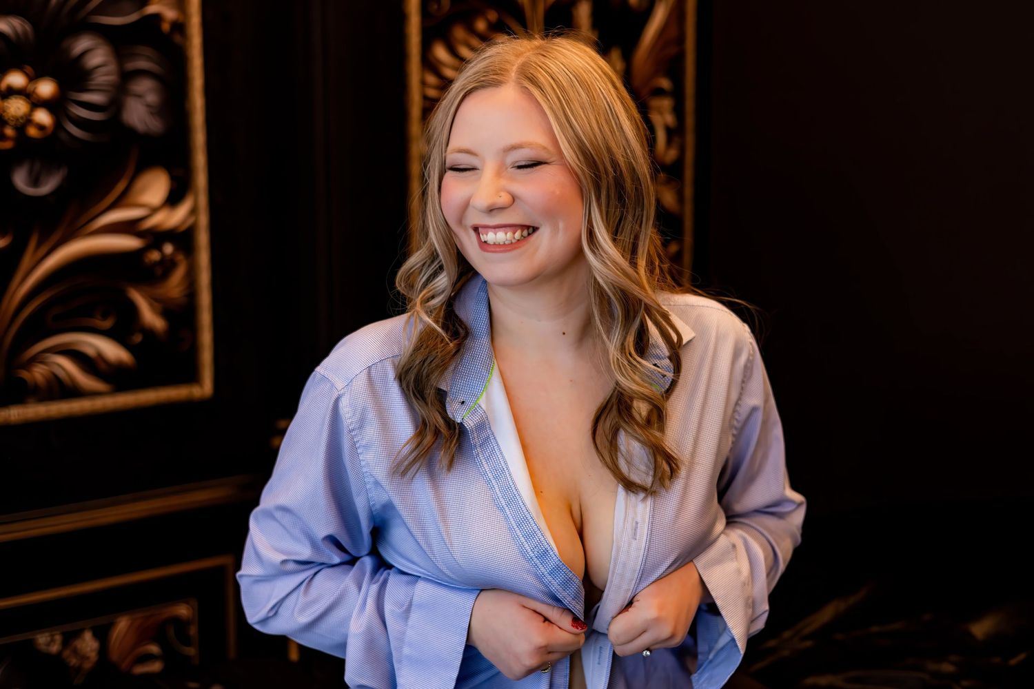 Playful boudoir session in light blue button-down shirt.