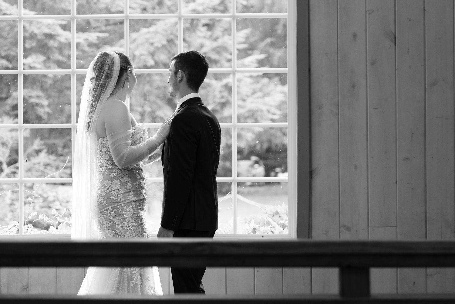 A bride and groom share intimate moments in black and white wedding photos against a rustic wooden backdrop. Captured by Savvy Photography