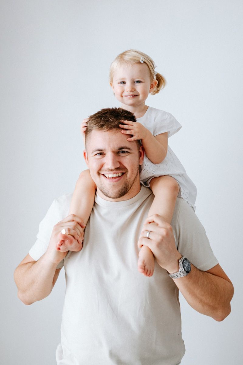 A series of playful candid moments between a parent and child wearing white against a light background.