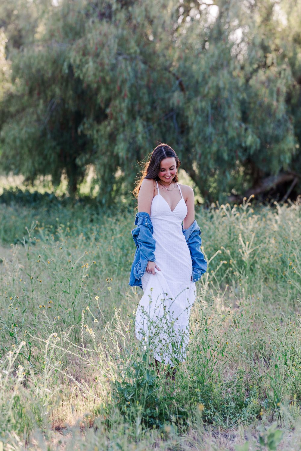 Simi High School senior posing in a grassy field with cowboy boots and guitar for outdoor senior portraits in Simi Valley.