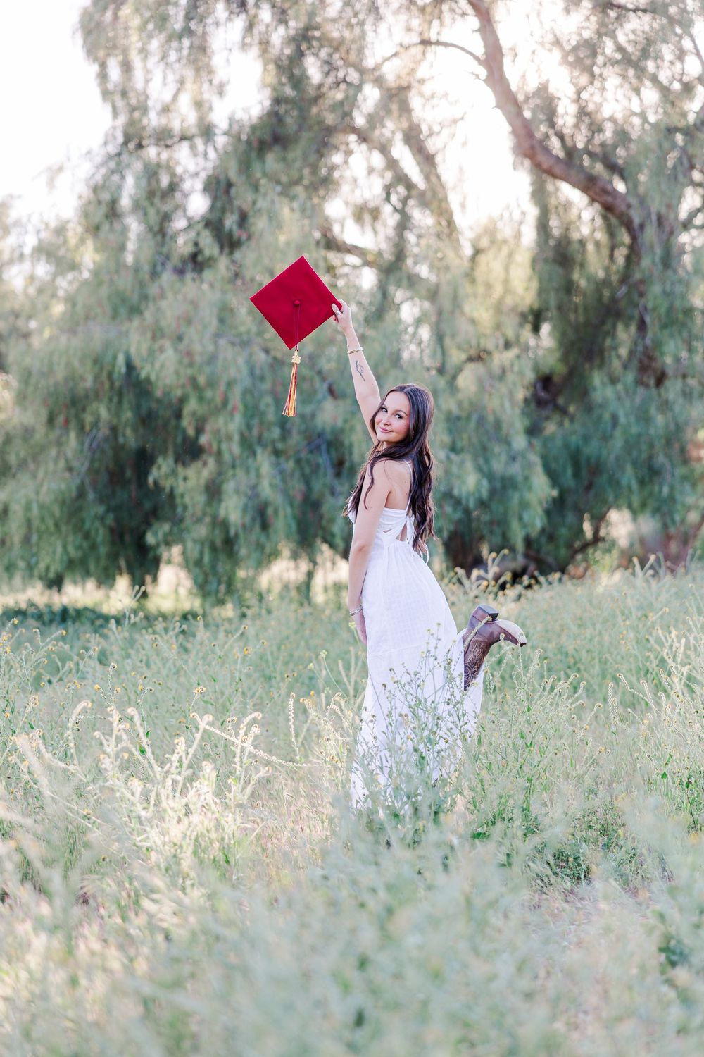 Simi High School senior posing in a grassy field with cowboy boots and guitar for outdoor senior portraits in Simi Valley.