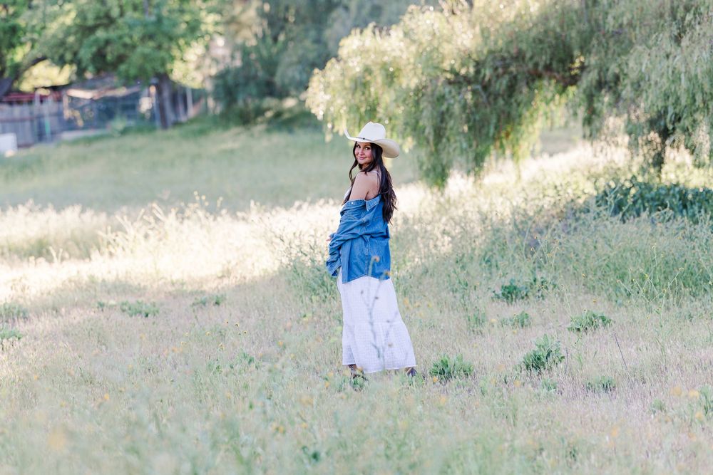 Simi High School senior posing in a grassy field with cowboy boots and guitar for outdoor senior portraits in Simi Valley.