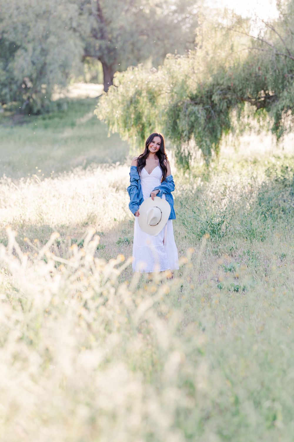 Simi High School senior posing in a grassy field with cowboy boots and guitar for outdoor senior portraits in Simi Valley.