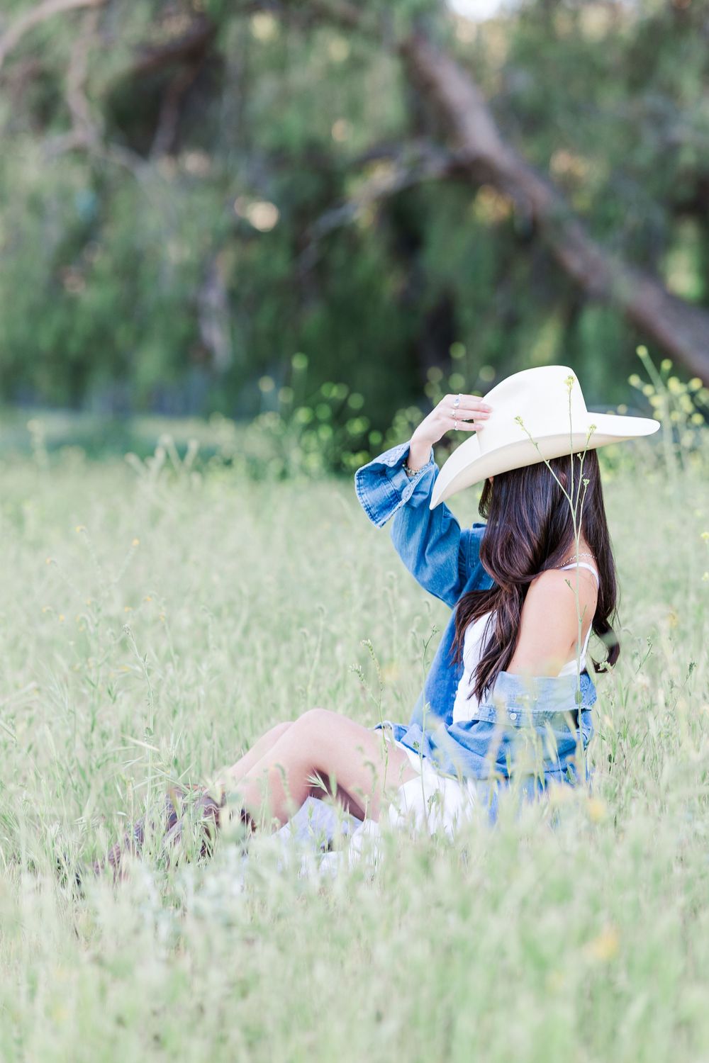 Simi High School senior posing in a grassy field with cowboy boots and guitar for outdoor senior portraits in Simi Valley.