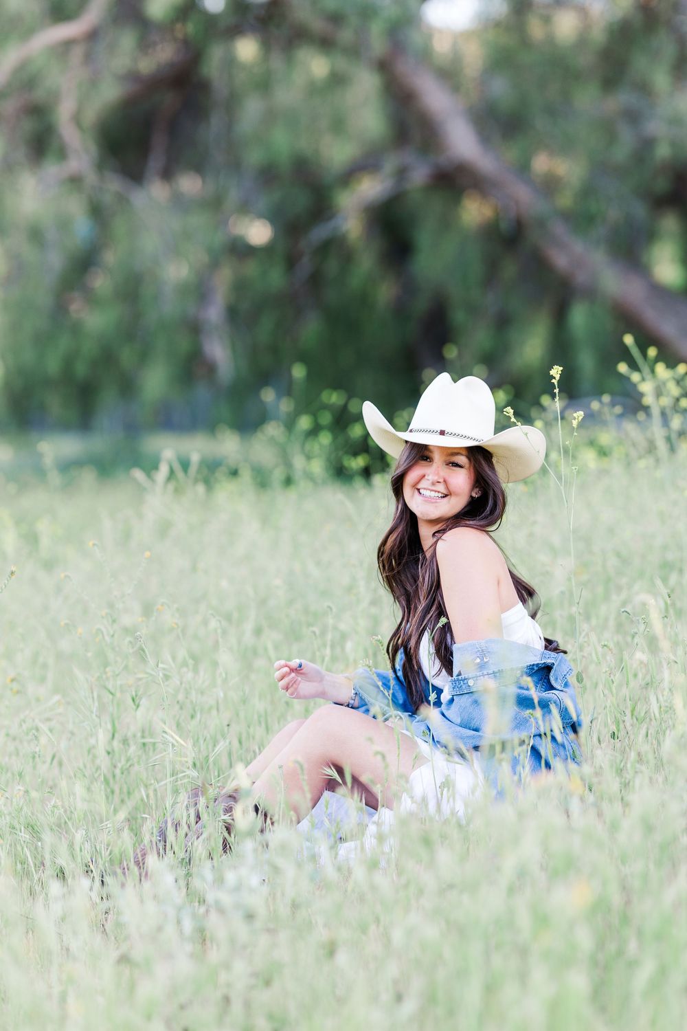 Simi High School senior posing in a grassy field with cowboy boots and guitar for outdoor senior portraits in Simi Valley.