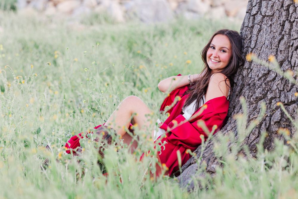Simi High School senior posing in a grassy field with cowboy boots and guitar for outdoor senior portraits in Simi Valley.