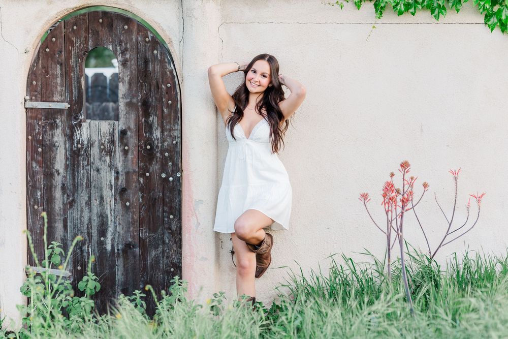 Simi High School senior posing in a grassy field with cowboy boots and guitar for outdoor senior portraits in Simi Valley.