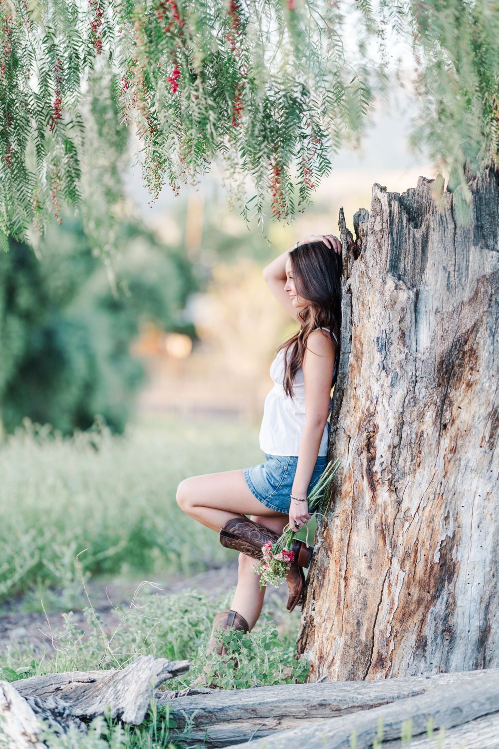 Simi High School senior posing in a grassy field with cowboy boots and guitar for outdoor senior portraits in Simi Valley.