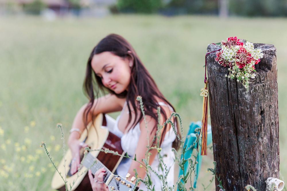 Simi High School senior posing in a grassy field with cowboy boots and guitar for outdoor senior portraits in Simi Valley.