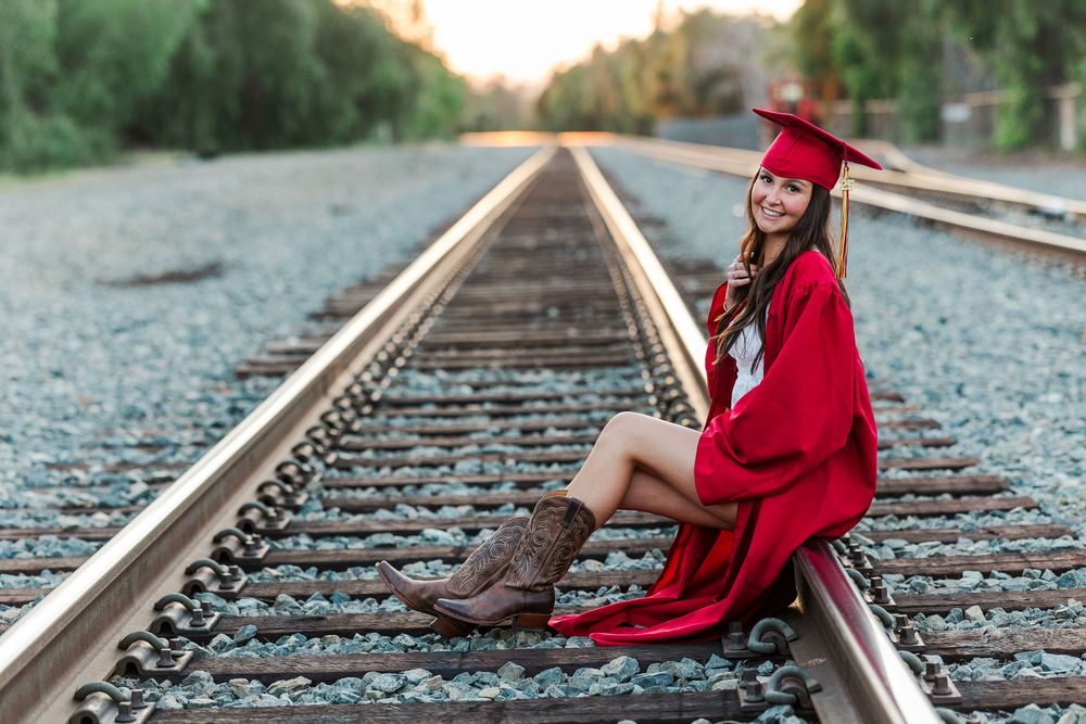 Simi High School senior posing in a grassy field with cowboy boots and guitar for outdoor senior portraits in Simi Valley.