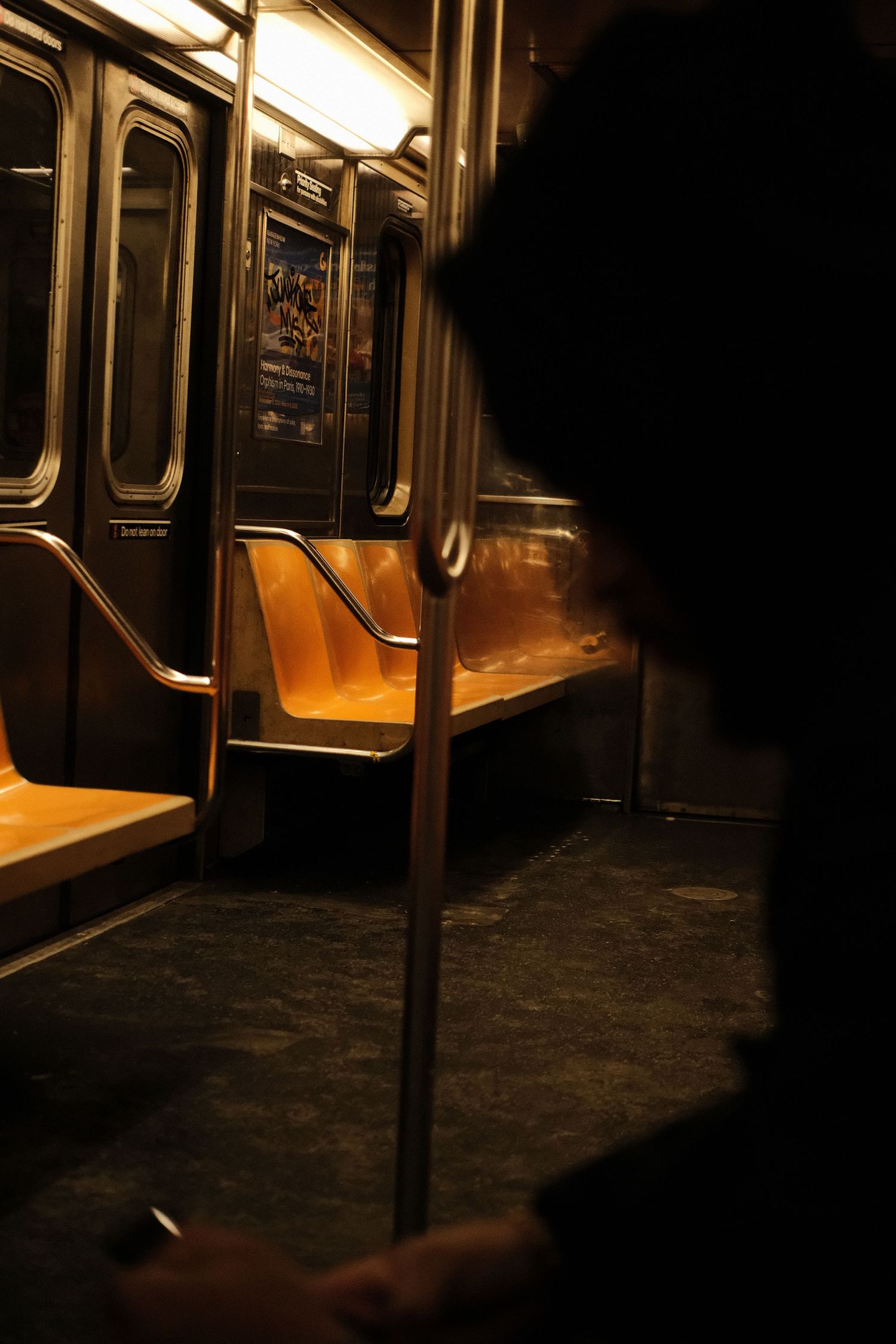 Dark and moody interior shot of an empty subway car with orange seats.