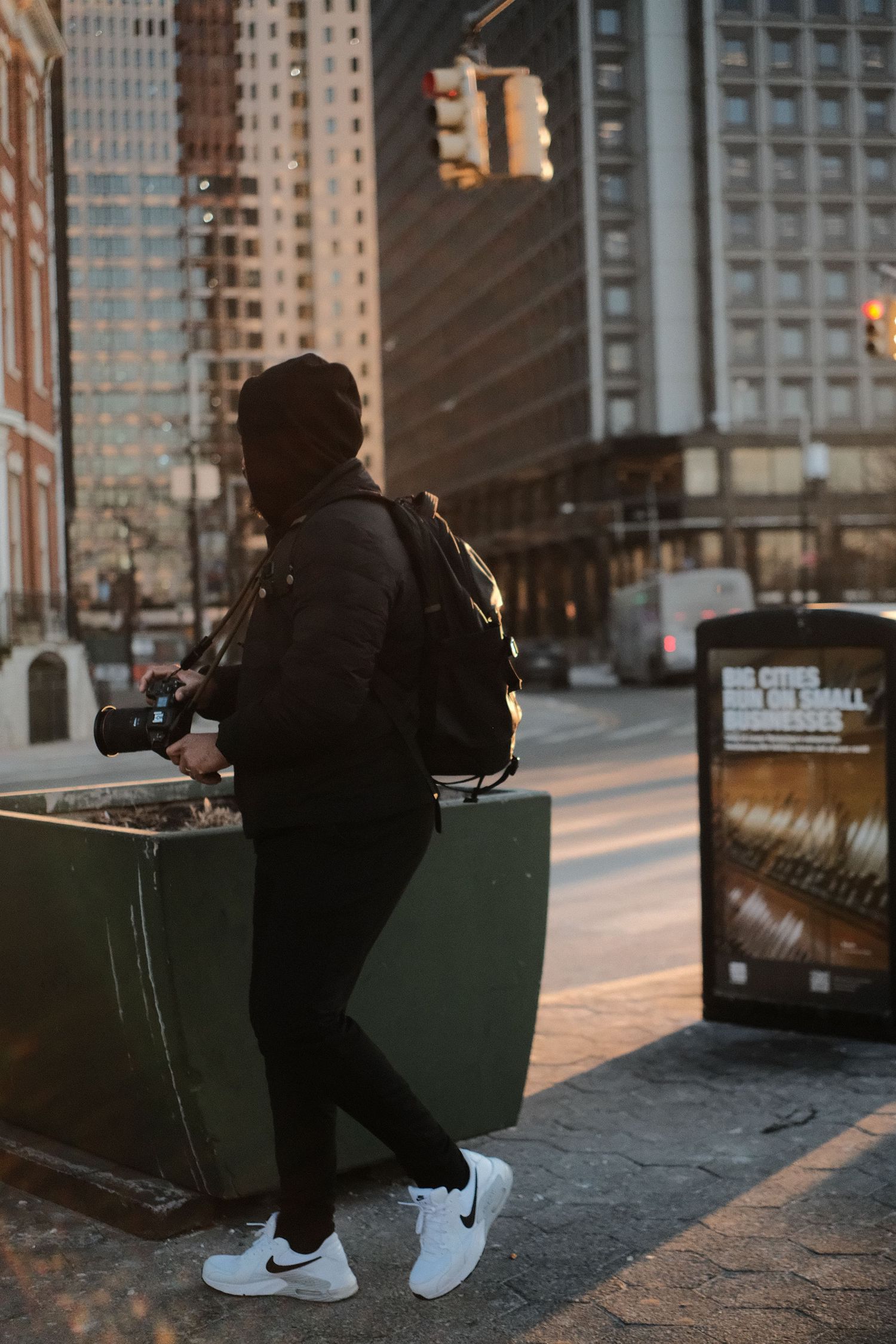 Silhouette of a person sitting on a bench at sunset near urban buildings.