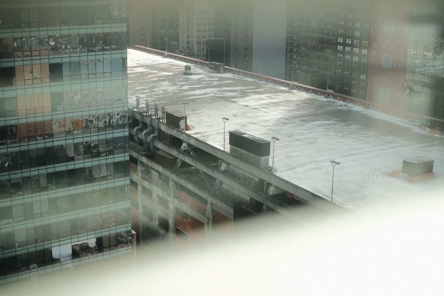 Aerial view of urban rooftop through misty window on rainy day.