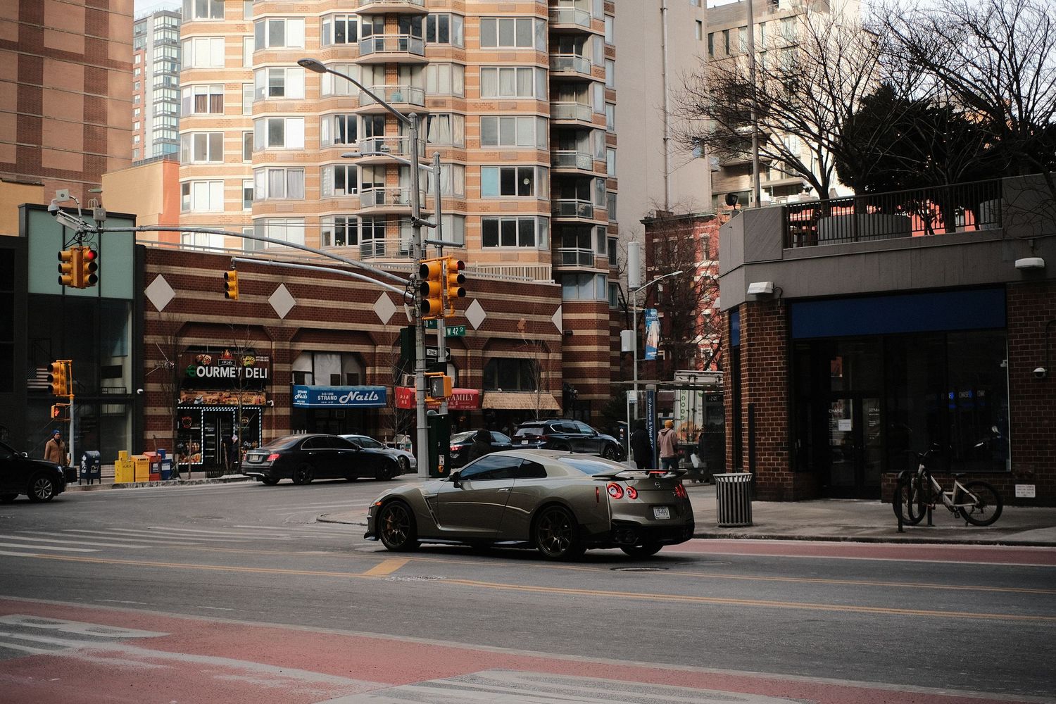Wide view of a city street with modern apartment buildings and commercial spaces in daylight.