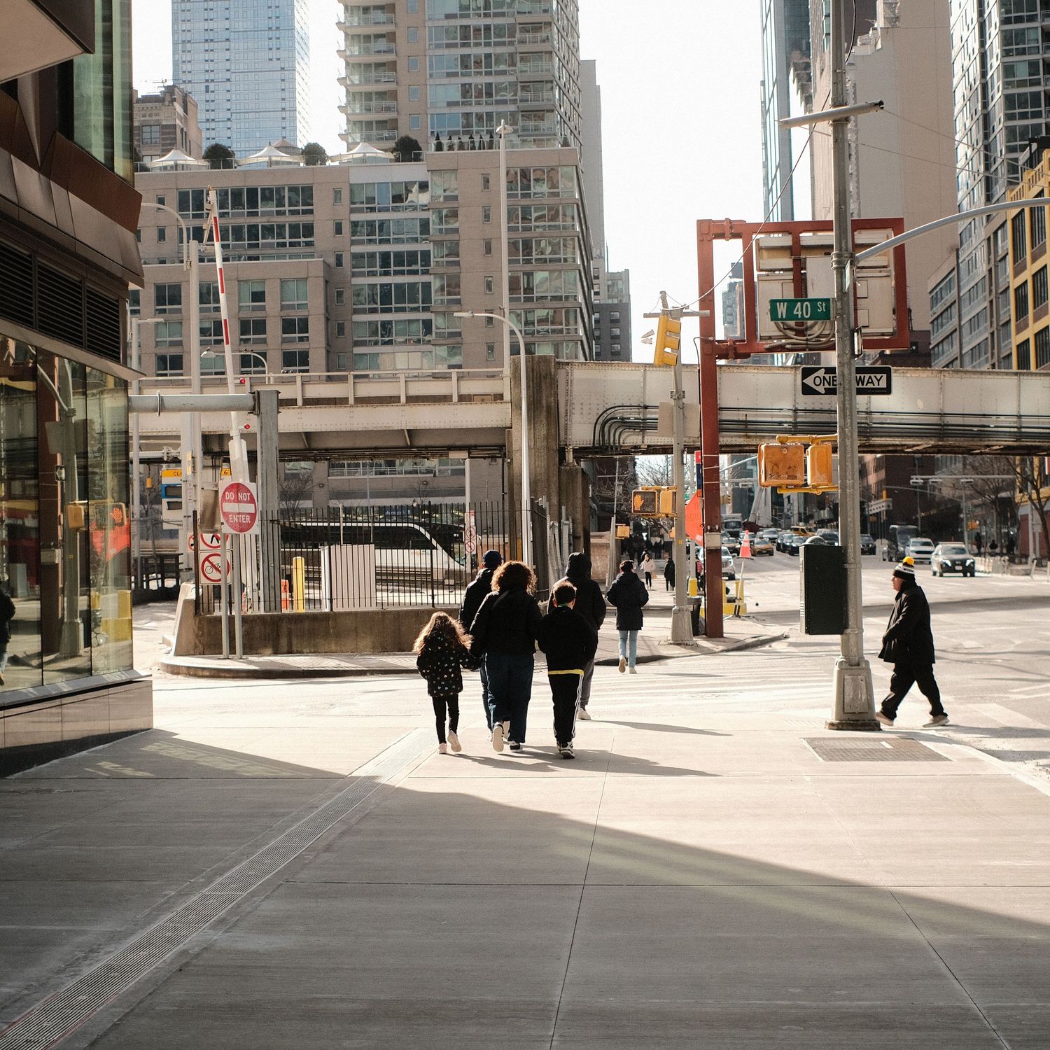Downtown street view with pedestrians walking near modern high-rise buildings and decorative posts.