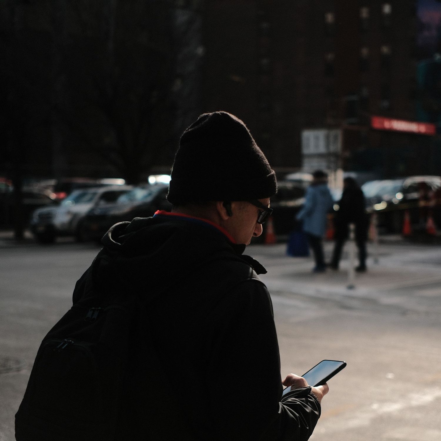 Silhouetted figures walking on an urban street during daytime.