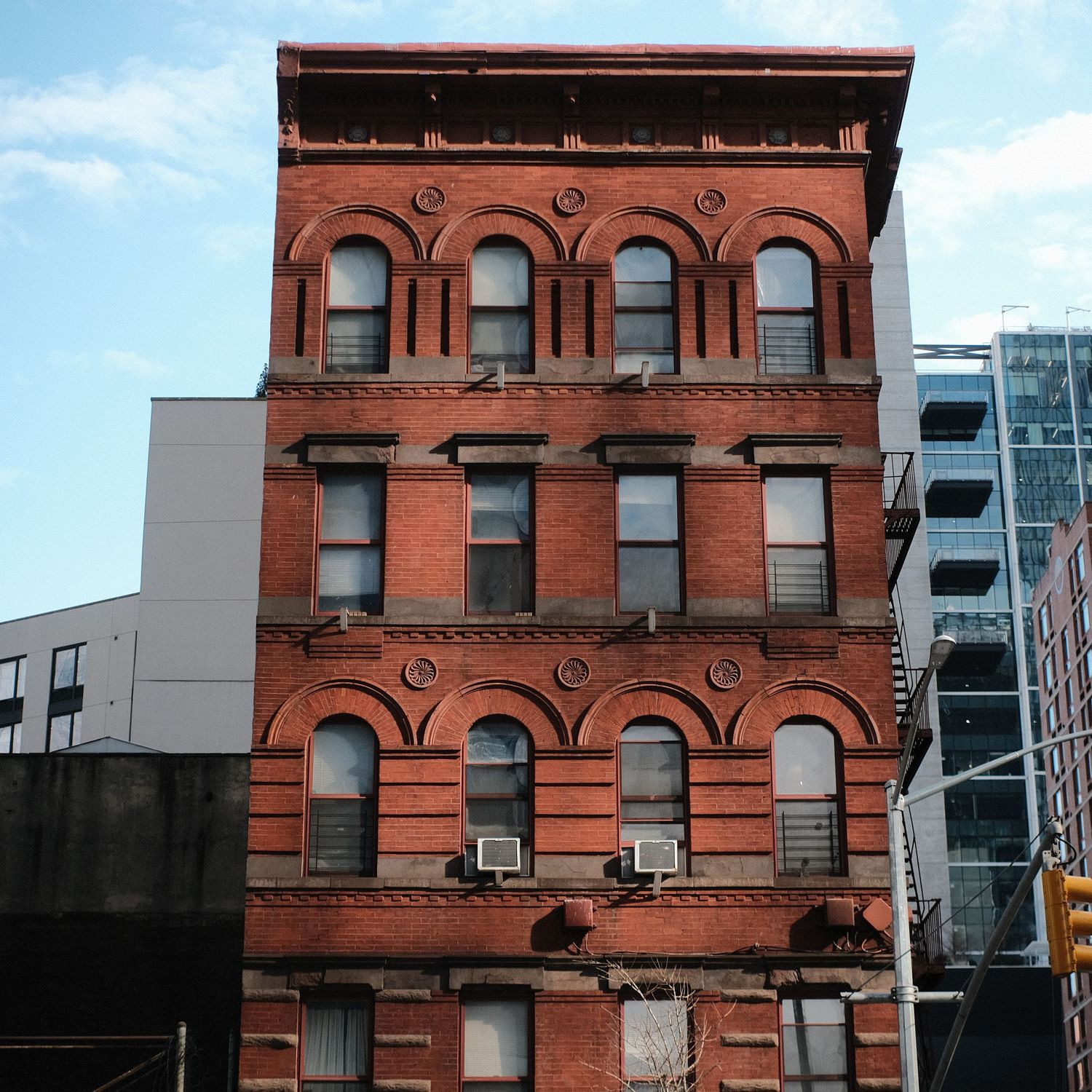 Historic red brick building with ornate architectural details and arched windows against blue sky.
