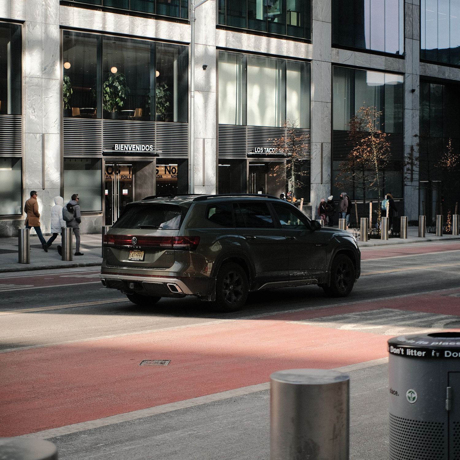 Modern SUV parked on a red-painted street section in front of a glass office building.