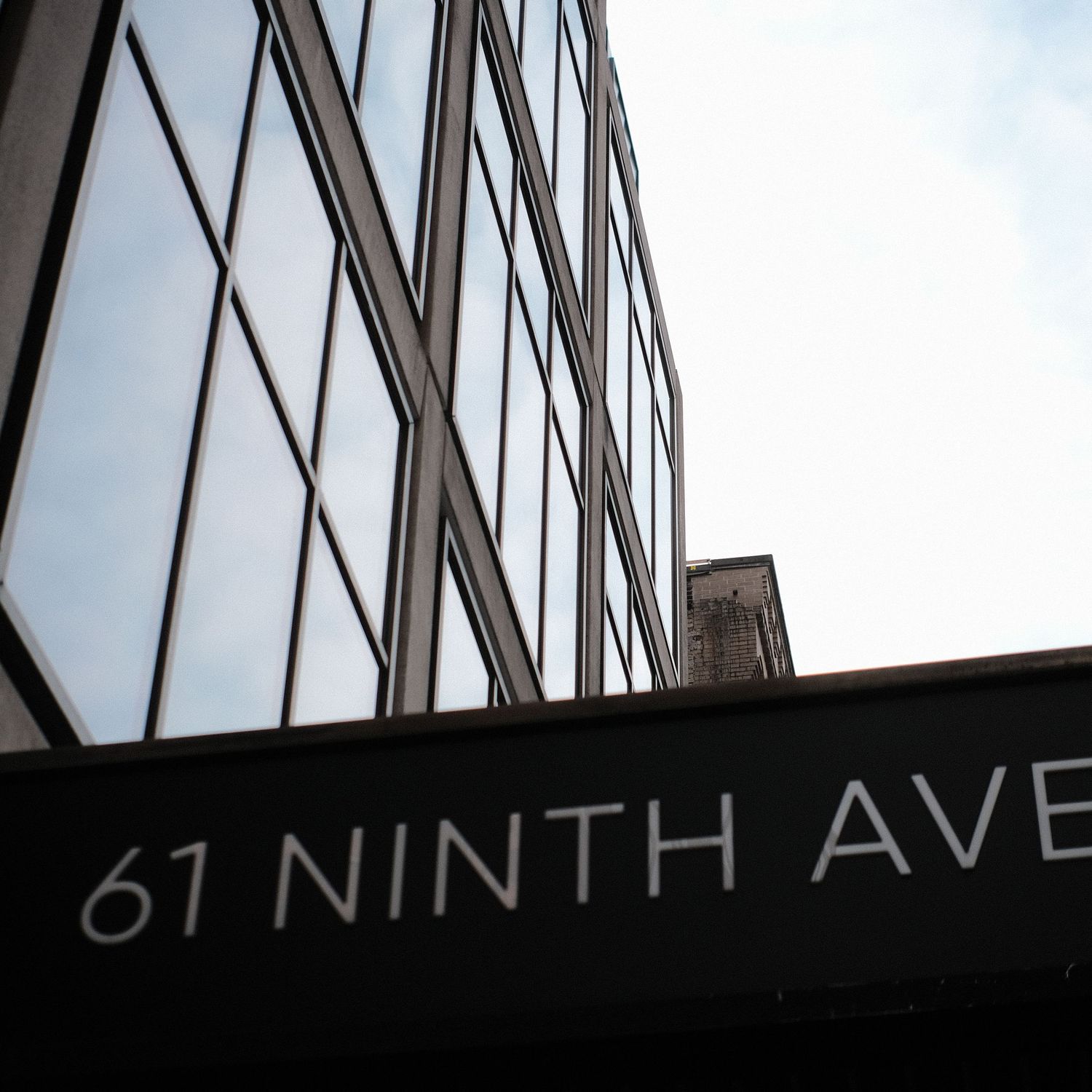 Urban architecture with a black sign showing '67 NINTH AVE' against a light background.