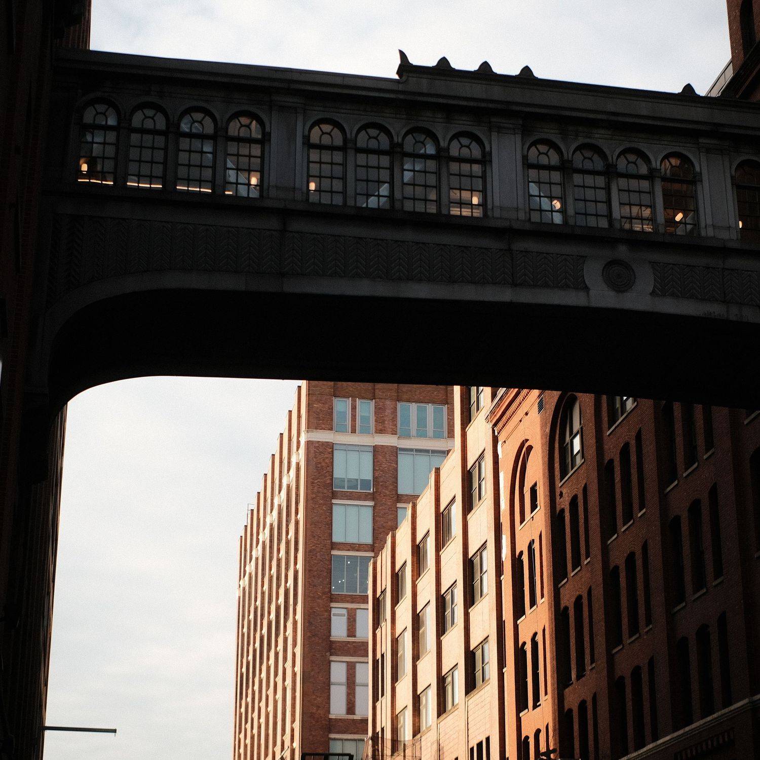 Red brick buildings with windows line an urban street under an overcast sky.