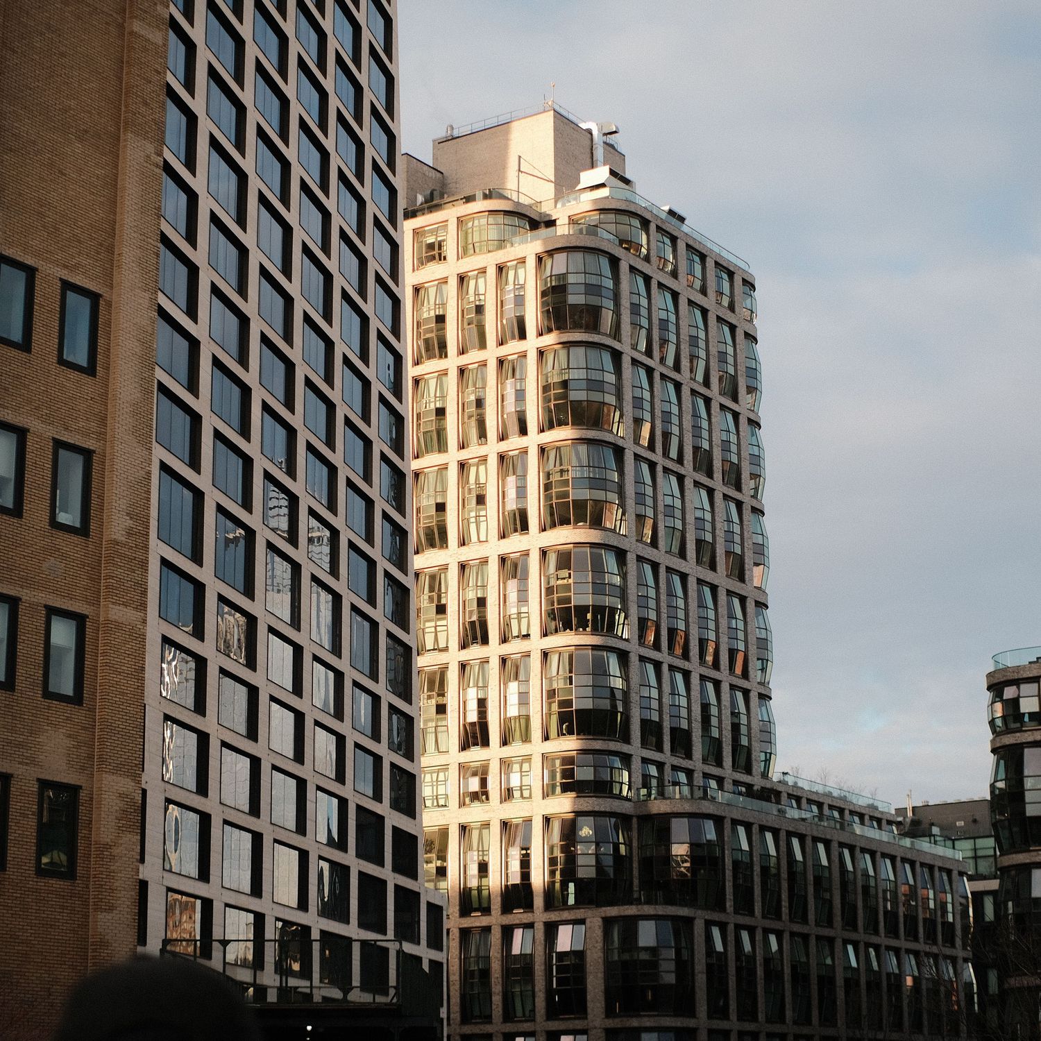 Modern high-rise building with geometric window pattern against cloudy sky.