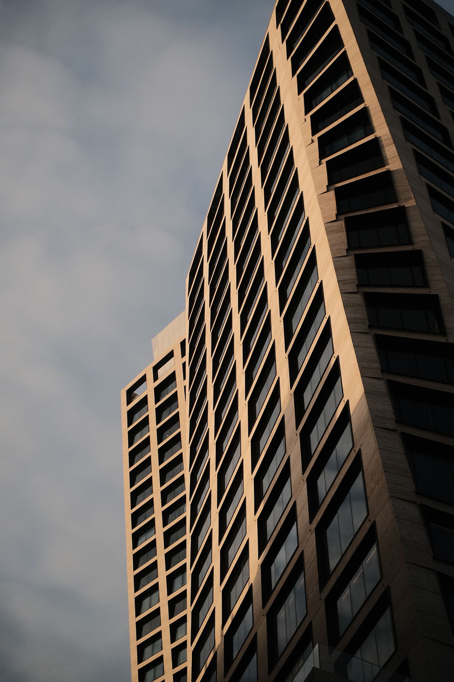 Angular modern office building facade with diagonal lines and windows catching afternoon light.