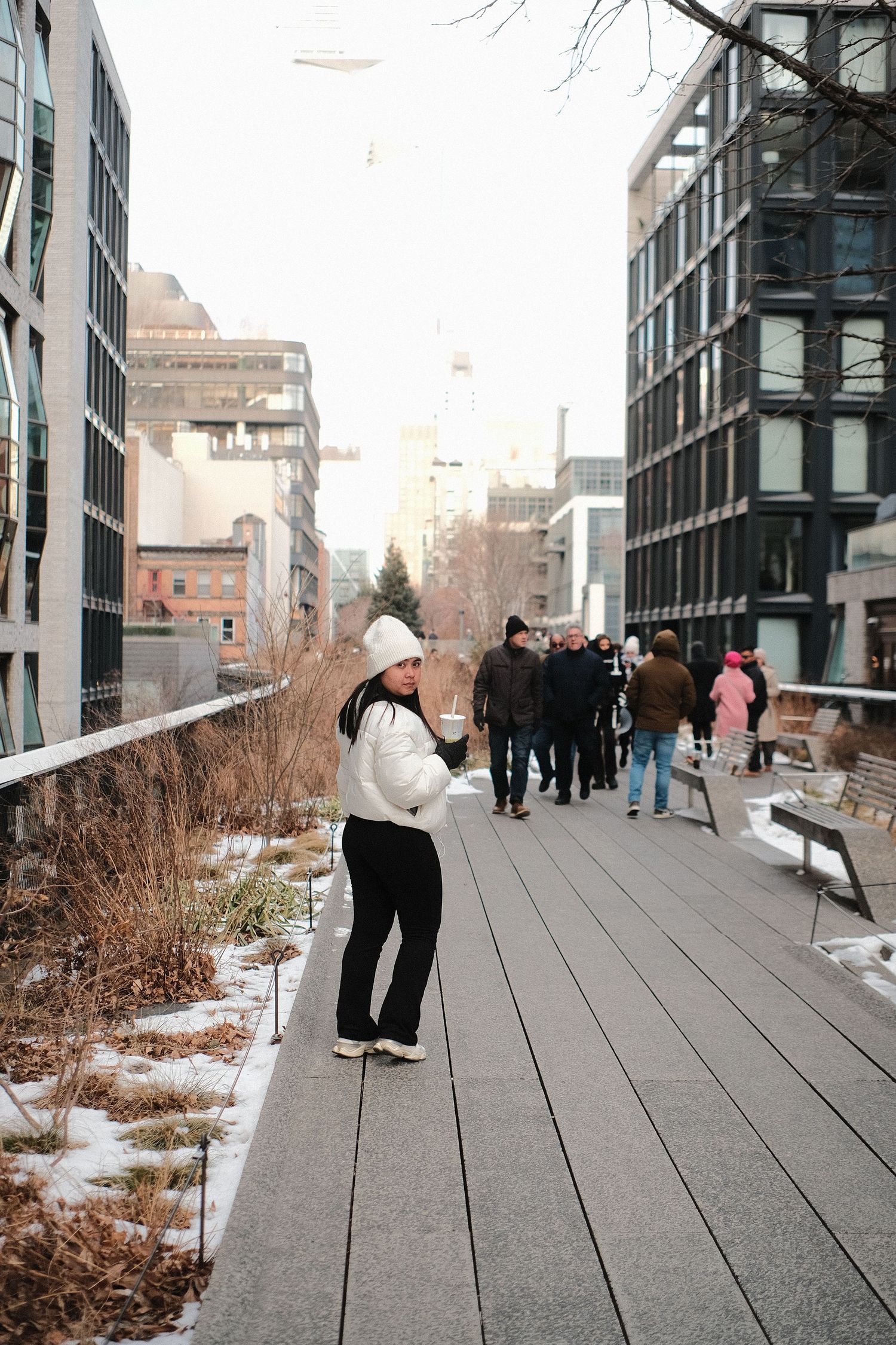 People walking along the High Line elevated park in winter with snow patches visible.