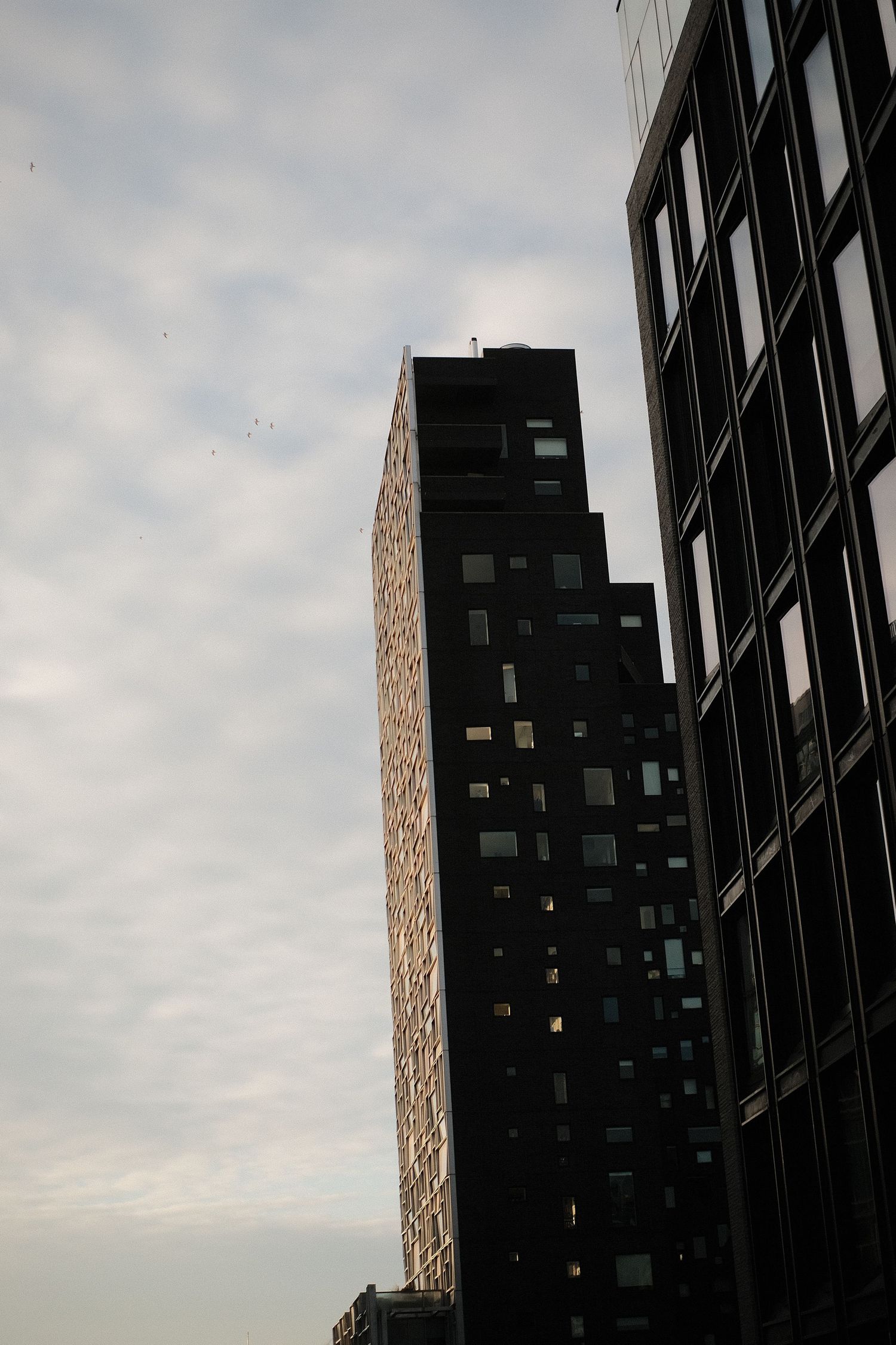 Modern high-rise buildings photographed against overcast sky at dusk.