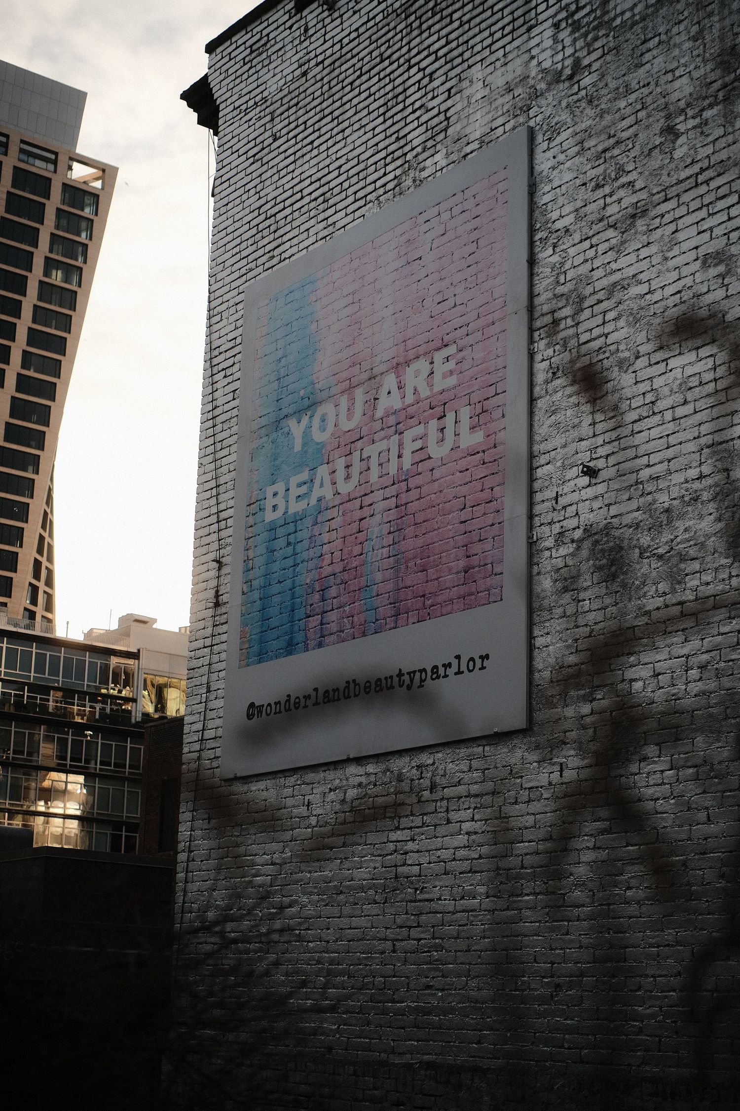 Faded advertisement on weathered brick wall with gradient colors visible.