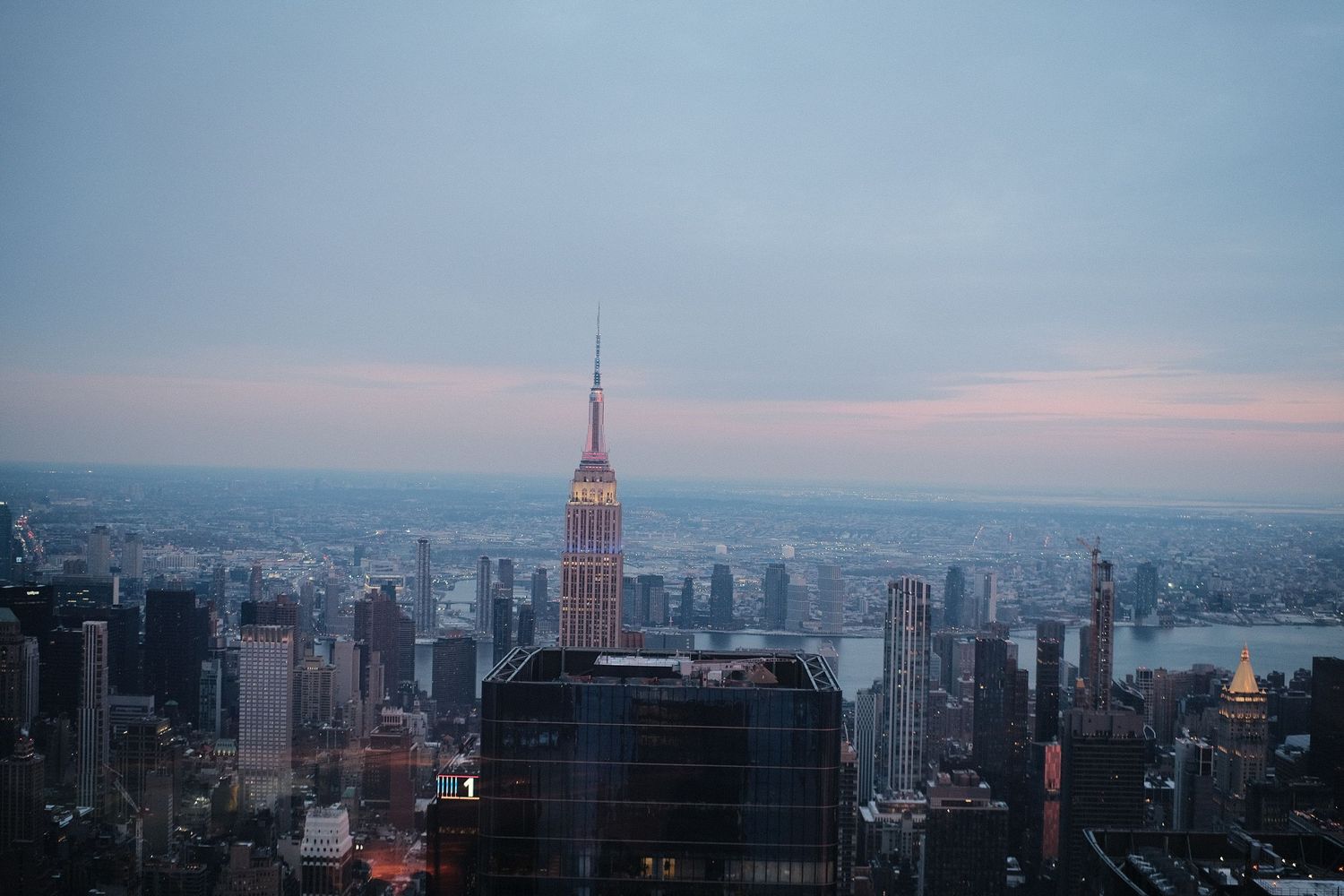 Aerial view of New York City skyline at sunset showing iconic buildings and urban landscape.