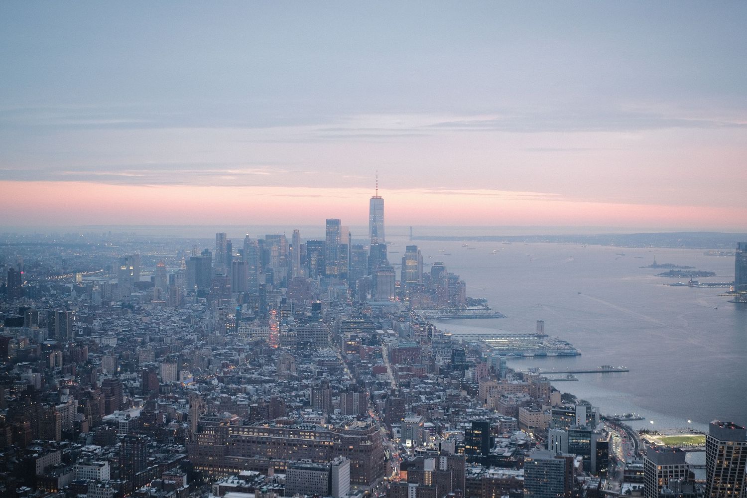 Aerial panoramic view of New York City skyline at sunset with tall skyscrapers and waterfront.