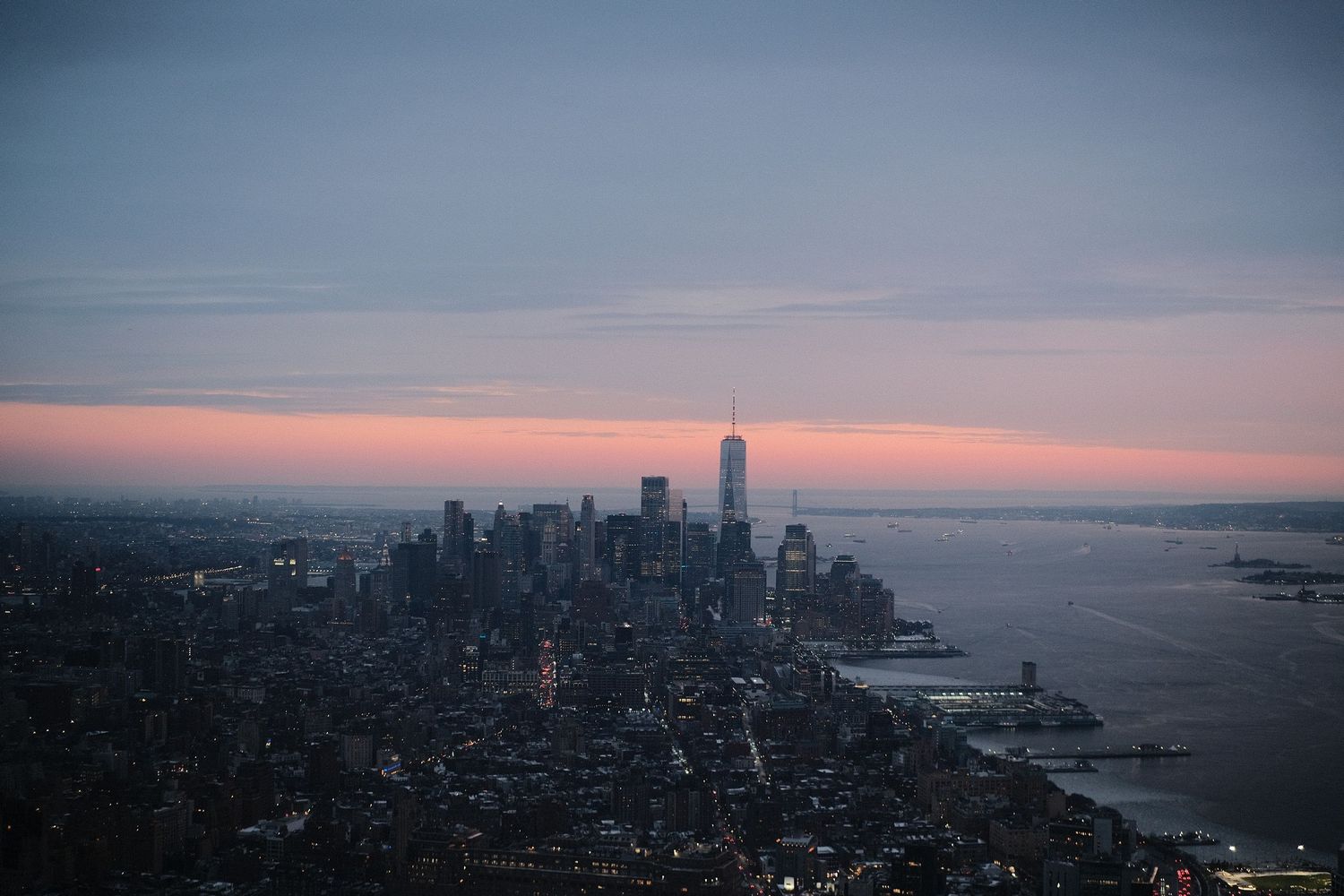 Panoramic cityscape showing urban architecture and coastline during dusk.