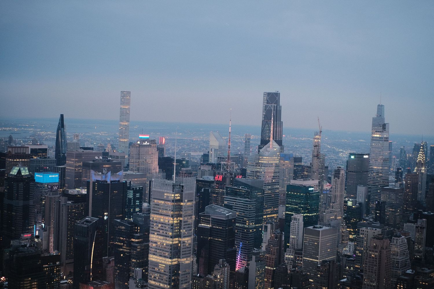 Wide angle view of Manhattan's modern skyscrapers against a hazy blue sky.