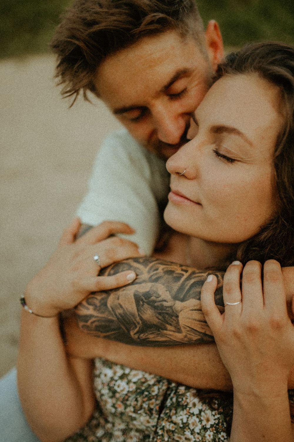 Tender embraces captured in warm tones against a natural outdoor setting.
