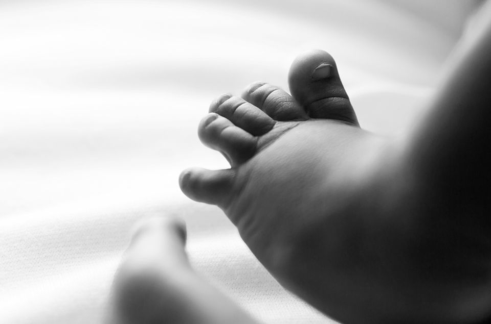 Close-up black and white image of hands writing with a pen on paper.