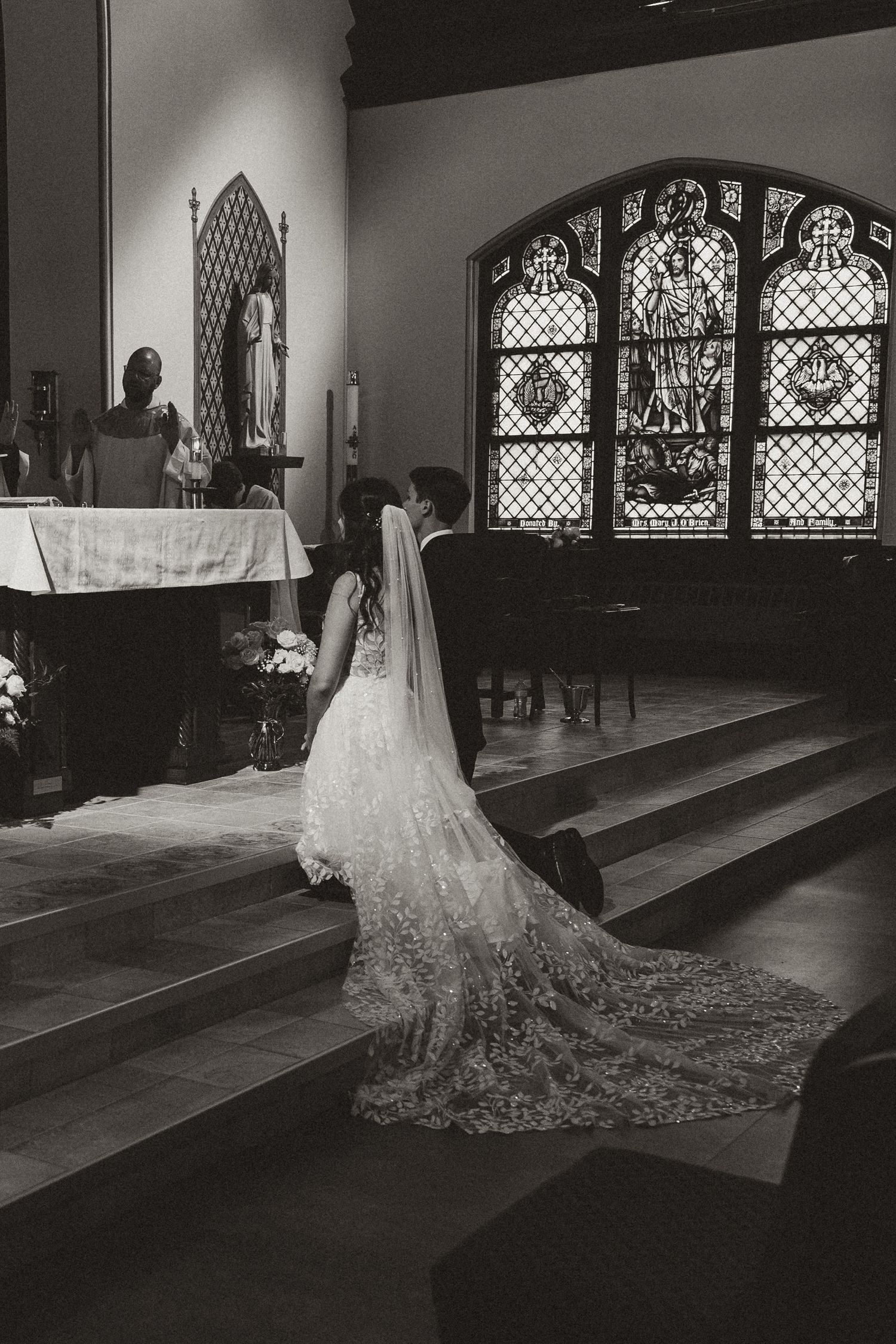 A dramatic black and white photo of a wedding dress with a long train in a church setting.