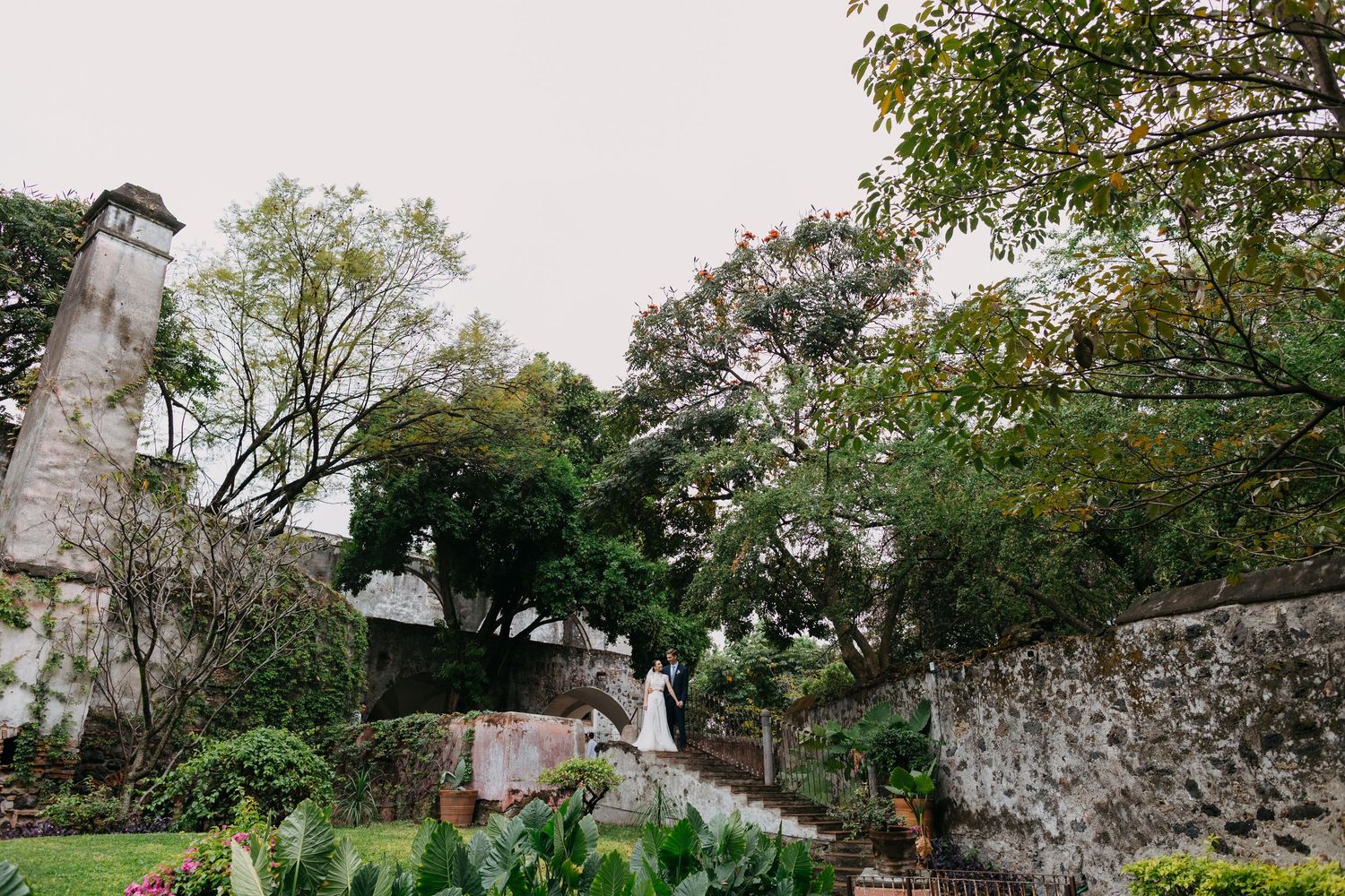Wedding ceremony setting against ancient stone walls and lush greenery.