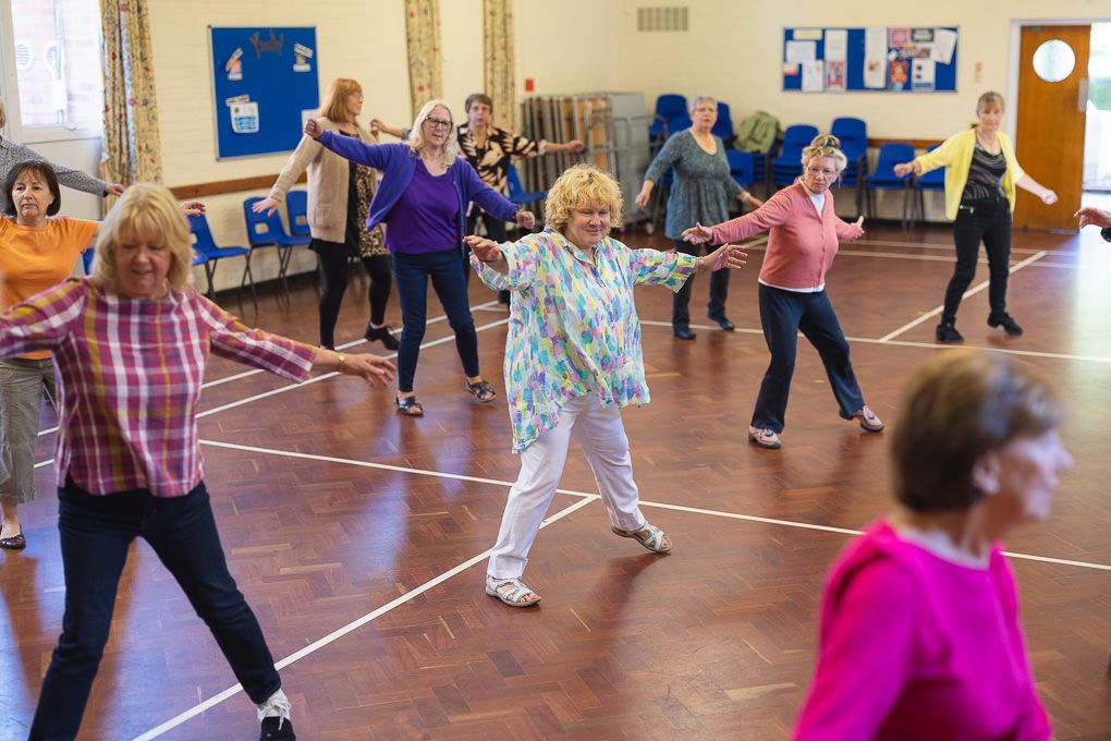 A group of people participate in a dance or exercise class in a bright indoor studio space in Letchworth, Hertfordshire.
